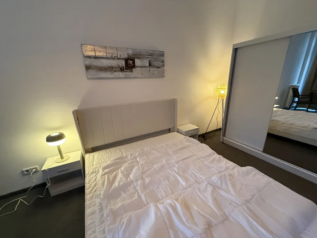 The assembled bedroom furniture with bed, bedside furniture and mirrored wardrobe.