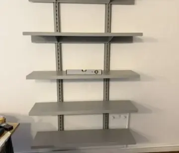 The installed grey shelves and vertical wall rails.